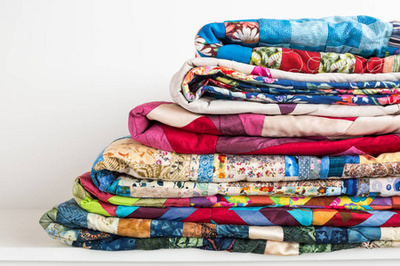缝纫, 拼凑和时尚的概念-美丽的彩色棉被的宏折叠和存储在几行高, 以存储, 成品纺织品在白色背景缝制产品销售